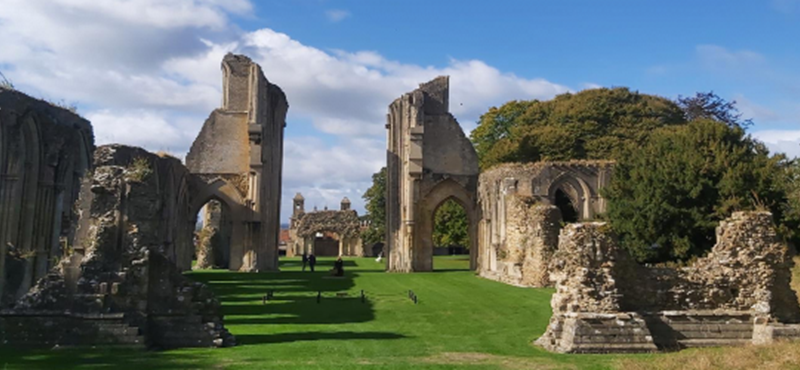 Blue sky and green grass with old large stones