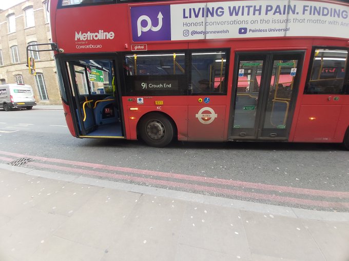 Picture of a red London bus, pulling up to the curb edge to put the ramp down