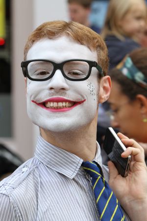 A photo of a man with a painted face holding a mobile phone.
