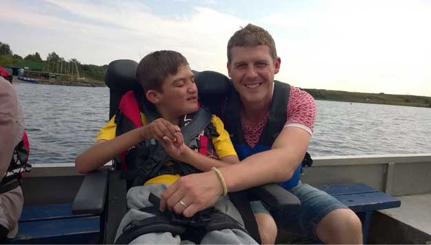 A photo of a man hugging a boy on a boat.