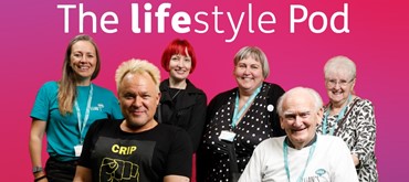 A photo of the Euan's Guide team in front of the pink Motability Lifestyle magazine backdrop