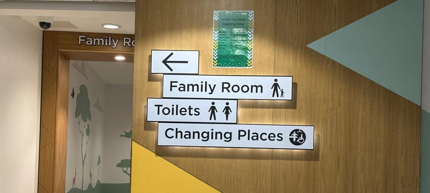 A photograph of signage pointing to Family Room, Toilets, Changing Places