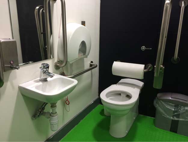 A photo of an accessible toilet with a green floor