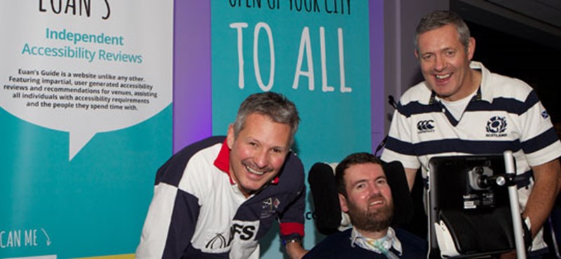 A photo of Euan with two men wearing rugby tops.