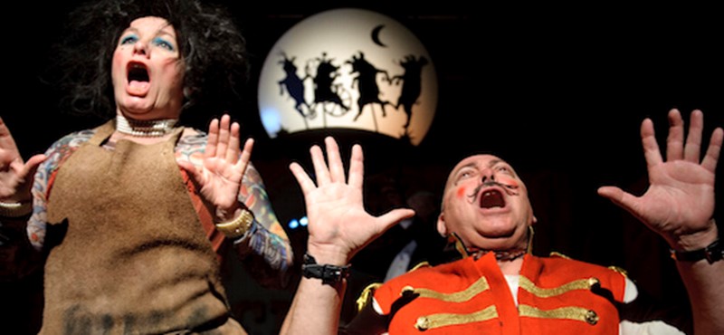 Photo of a man and a woman singing in circus costume.