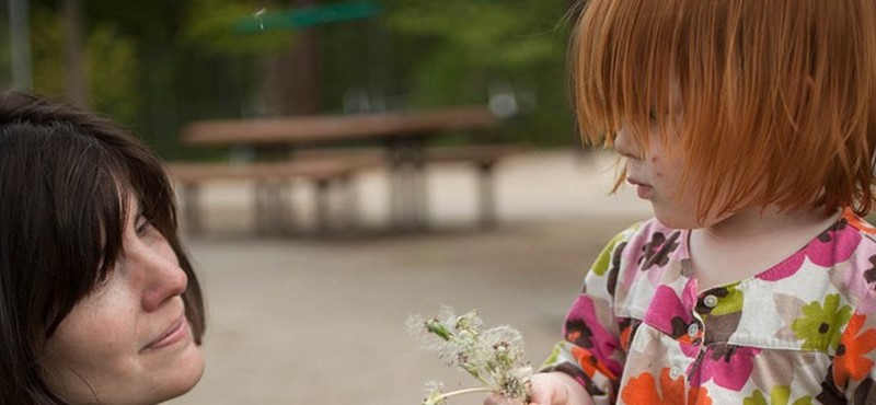 A photo of a child giving a woman a flower.