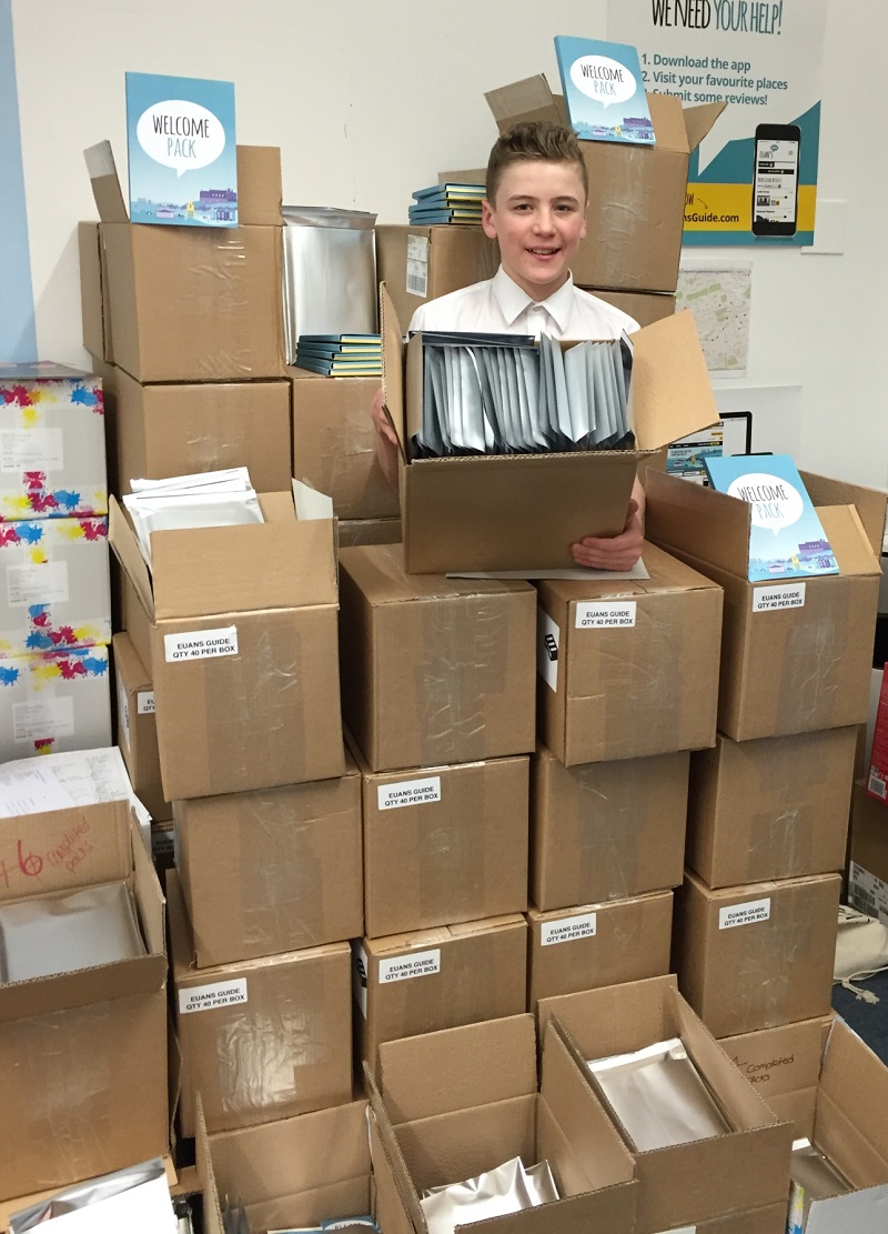 Photo of our volunteer Lewis surrounded by boxes.