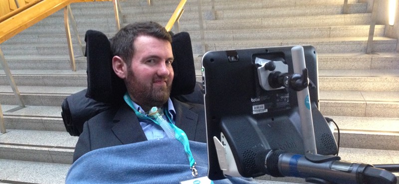 A photograh of Euan in front of steps at the Scottish Parliament