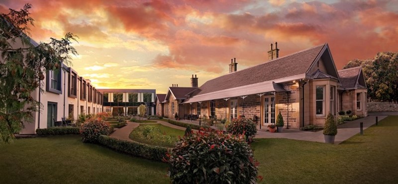 An exterior shot of the Ness Walk Hotel with a cloudy orange sun set 