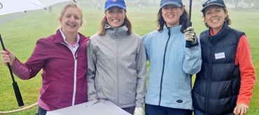 A Pictture of Euan's Guide Board members smiling and holding Euan's Guide Golf umbrellas.