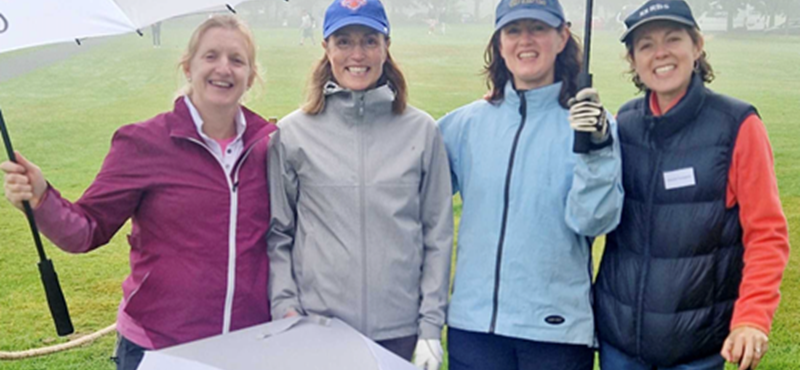 A Pictture of Euan's Guide Board members smiling and holding Euan's Guide Golf umbrellas.