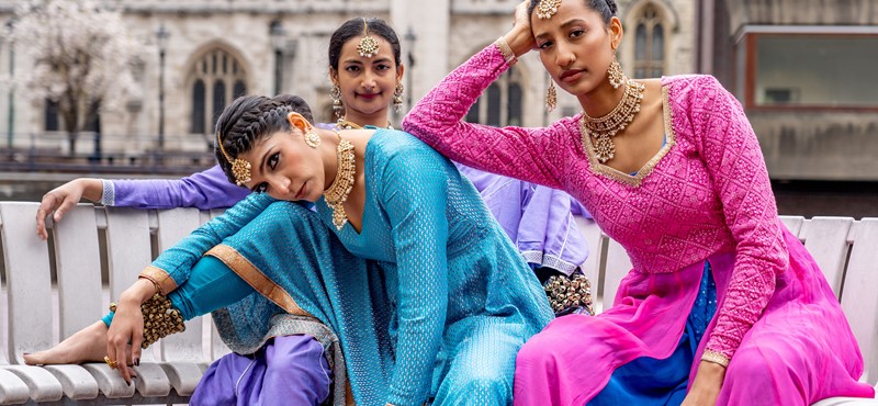Milton Keynes-based Pagrav Dance Company of three British Asian women look to camera while leaning on each other and wearing bright coloured clothing
