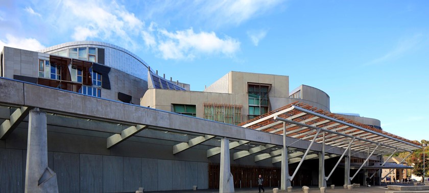 A photograph of the exterior of the Scottish Parliament building with blue skies above