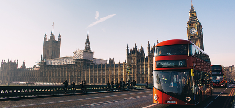 A photograph of a red London bus against a London skyline