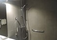 Shower with curtain pulled back so both grab rails can be seen