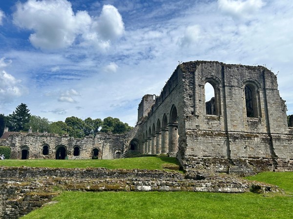 Image of a stone building with arches and grass