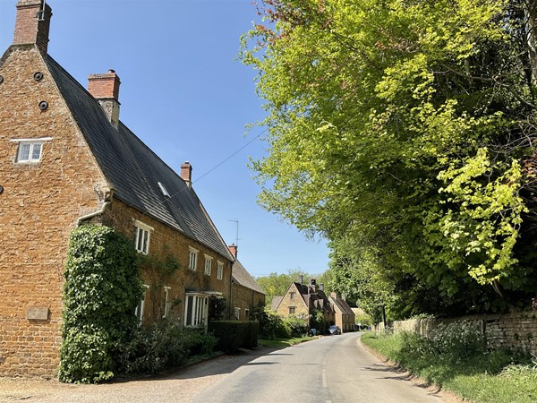 Image of a road with houses on one side and trees on the other