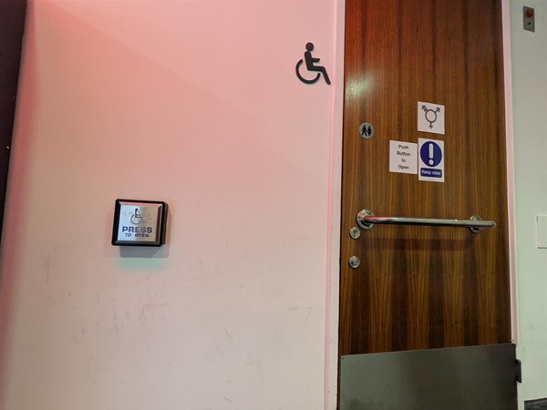 Image of Changing Places accessible toilet from the outside with horizontal grab rail and a button to open the door