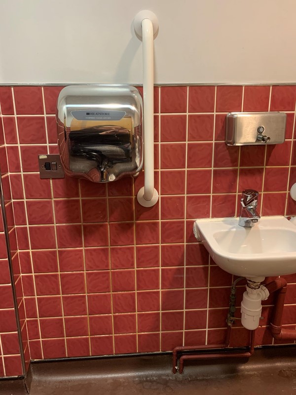 Image of sink with vertical handrails on both sides and dryer