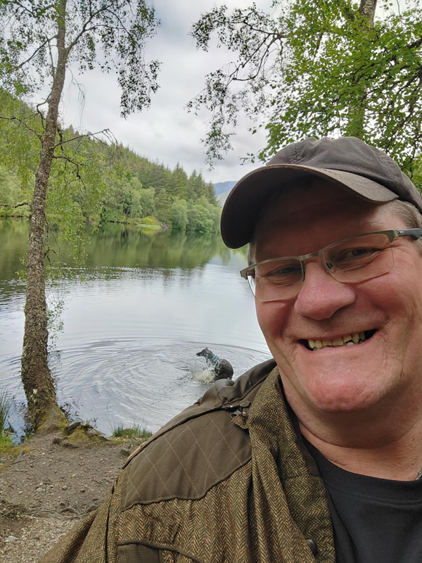 A man with glasses and a hat smiling