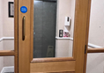 Access to the lifts was through a door that was too heavy to open independently. Photo shows a lift with a door and glass frame to get to it.