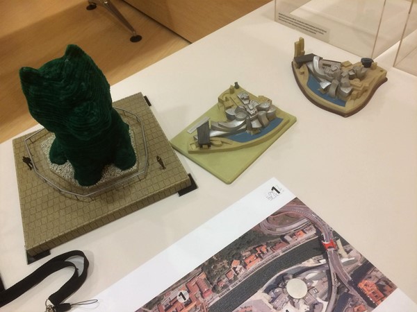 scale models showing the Guggenheim building, Koons puppy with humans for scale, and tactile book