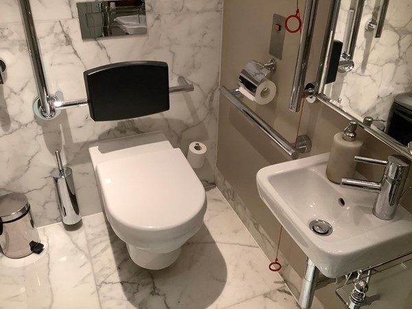 guiding you along to the toilets, one of which is an accessible toilet, with lovely grey and white tiles that complement the highly polished stainless bars and modern white furnished bars with grab rails and pull cord