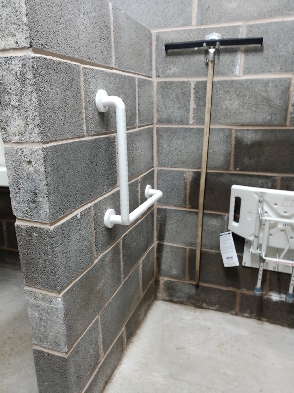 Accessible shower with concrete floor and breeze block walls