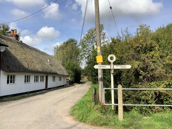 Signpost and thatched house