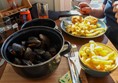 Freshly prepared fishcakes and chips and a pan of mussels.