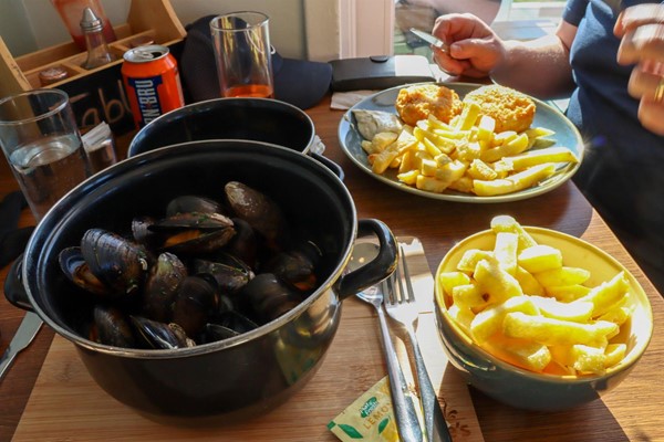 Freshly prepared fishcakes and chips and a pan of mussels.