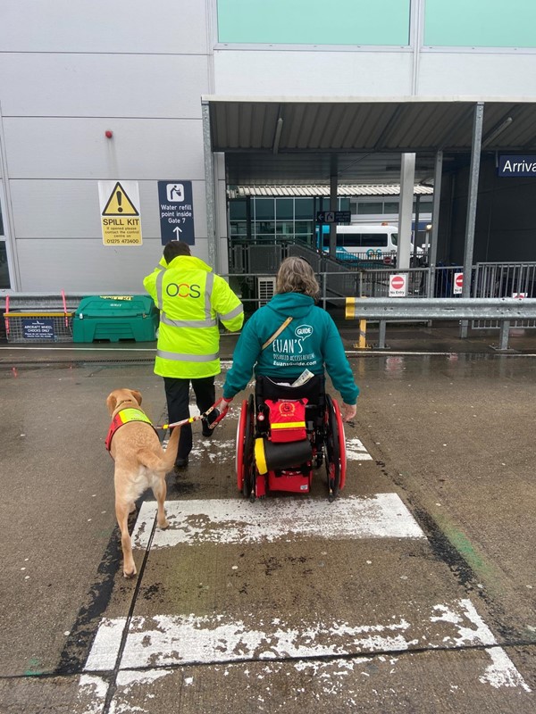 Image of a wheelchair user, assistance dog and someone in a hi vis jacket at Bristol Airport
