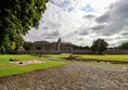 Museum grounds with cobbles and a rough path up to the gate.