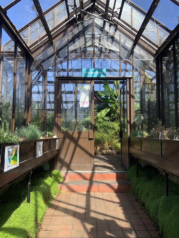 Image of the greenhouse entryway. There are two steps leading up to a double door.