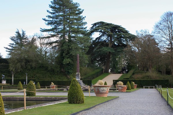 Formal gardens with pebble surface and hill in the distance.