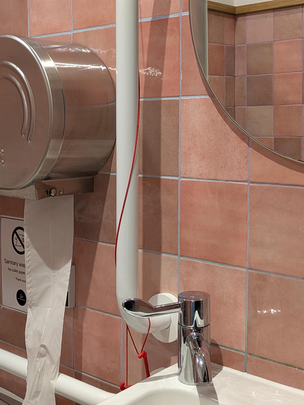 Image of red cord wrapped around grabrail at the sink.