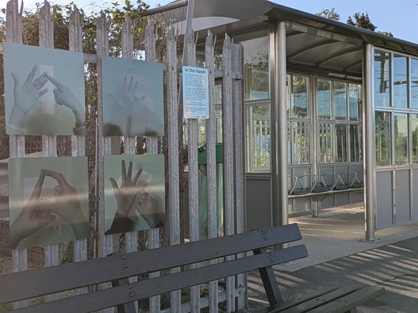 Image of rain shelter, the fence nearby has several BSL signs are part of an exhibit