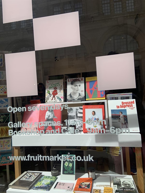 image of a window display with books and writing on the window with opening times and web address
