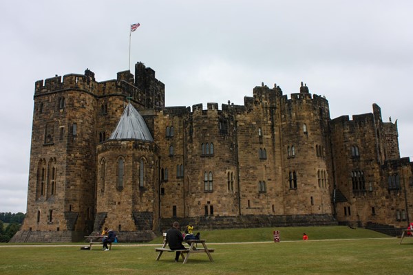 Main castle across the grass. There are some picnic tables on the lawn.