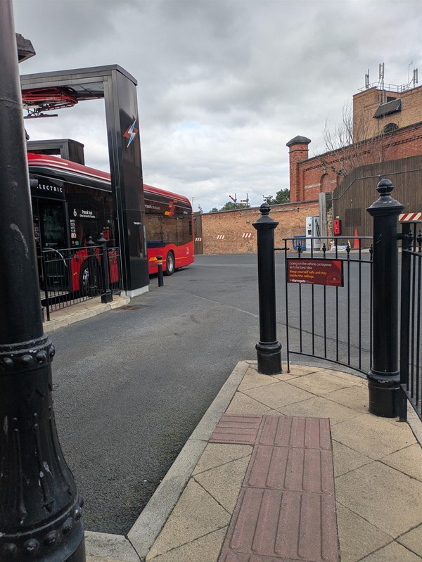 Image of a red bus, pulling into a bus stance