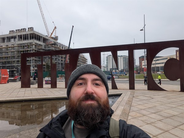 Image of Joe, a white man with a brown beard in front of the Titanic sign