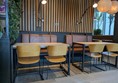 Image of yellow wooden seats at a table, there are brown leather bench seats at the back