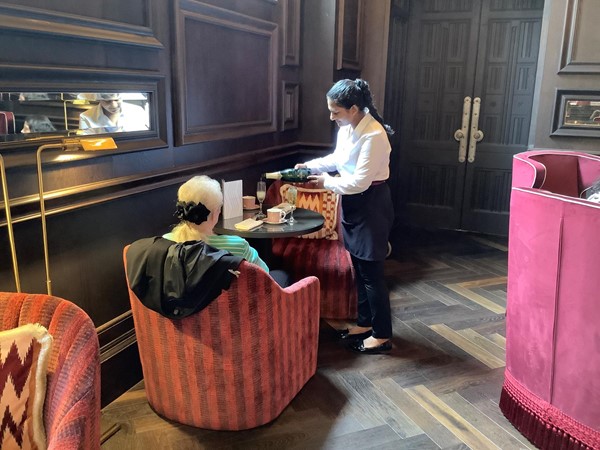 A waiter serving afternoon tea to a customer sitting at a table