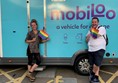 Mobiloo was in attendance - picture shows two people, a woman and a man, either side of the mobiloo sign on the mobiloo van. Each person is holding a pride rainbow flag.
