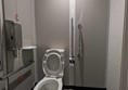 Image of the accessible toilet showing the toilet, grab rails, red cord and paper towel dispenser