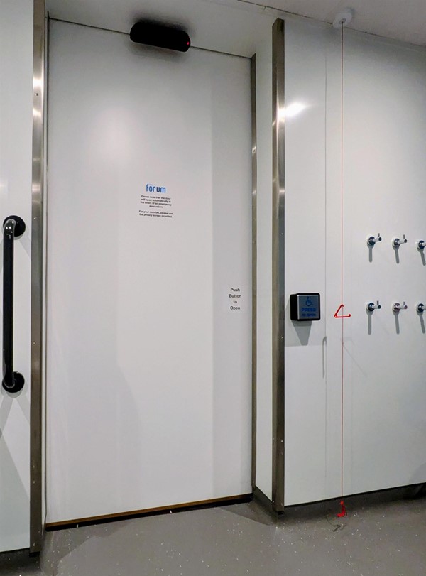 Image of accessible toilet door from the inside with emergency red cord and coat hooks