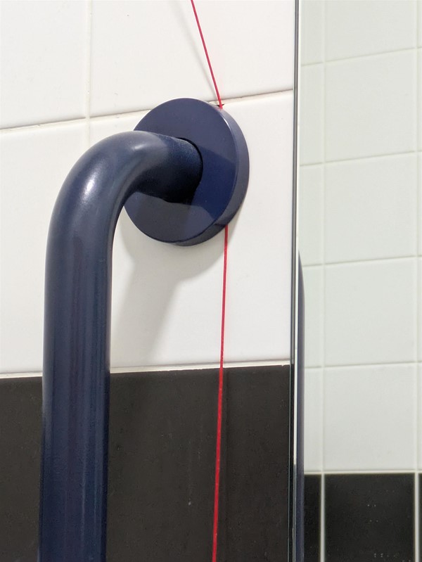 Image of red cord pinned behind grab rail