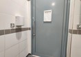 The toilet door lacks a grabrail on the inside, making it impossible for a wheelchair user to close the door from the inside. The mechanical hand-dryer is positioned too high for a wheelchair user to use it.