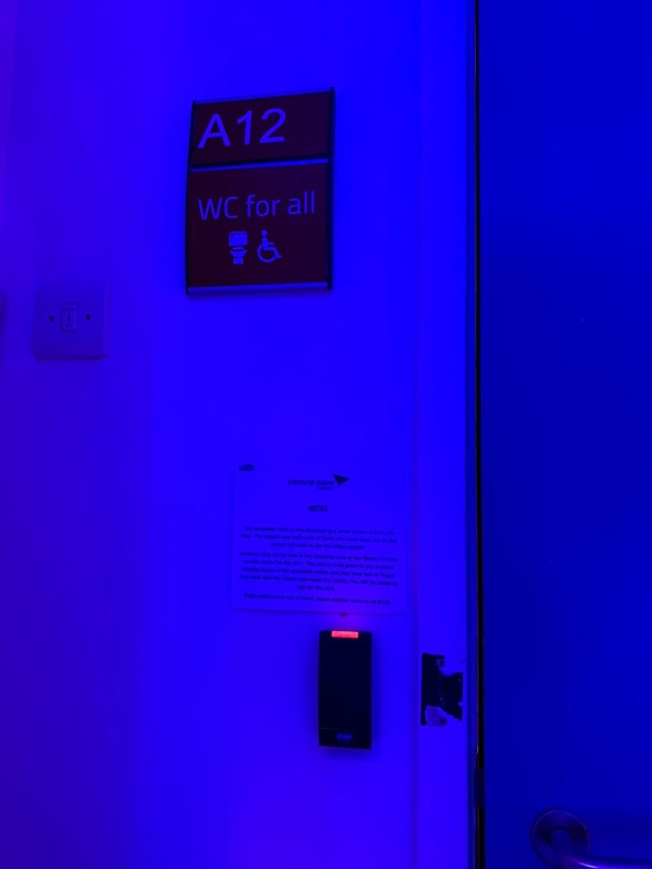 Image of outside of bathroom. Sign says A12 WC for All.