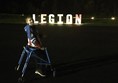 Child walker user in front of lit sign saying 'Legion'